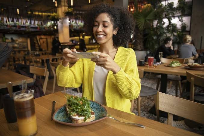 Cliente fotografando o prato no restaurante para avaliar a experiência